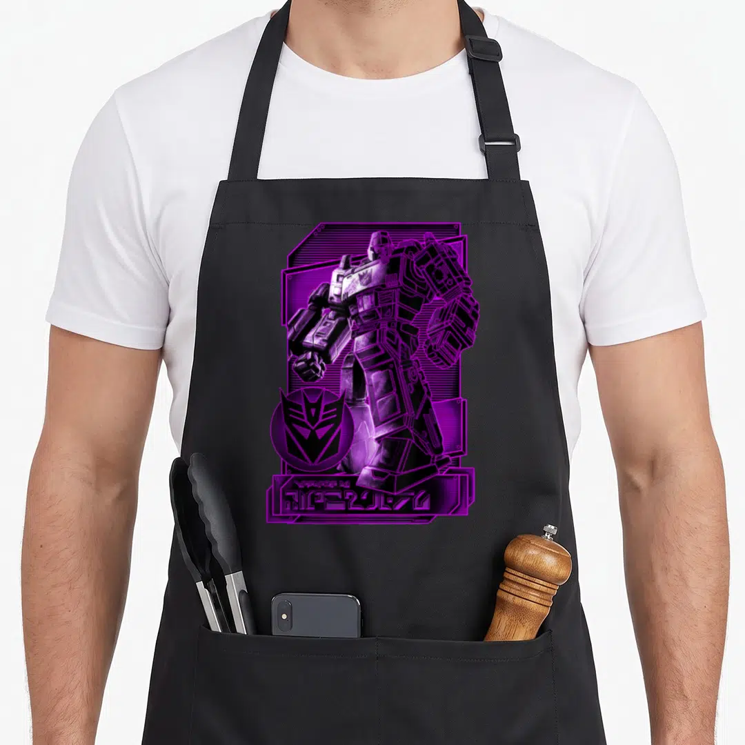 Megatron transformer apron - Standing robot in purple and black with circular logo and stylized text at bottom — shown on a black cotton canvas apron against a white background