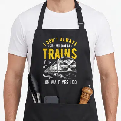 Alway locomotive apron - Distressed yellow and white train illustration with quote I don't always stop and look — shown on a black cotton canvas apron against a white background