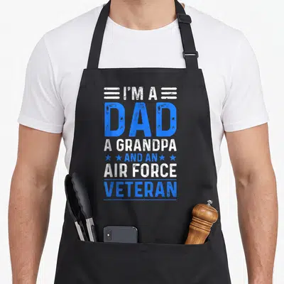 Force grandpa apron - Distressed blue and white text I'm a Dad Grandpa Air Force Veteran with four stars — shown on a black cotton canvas apron against a white background