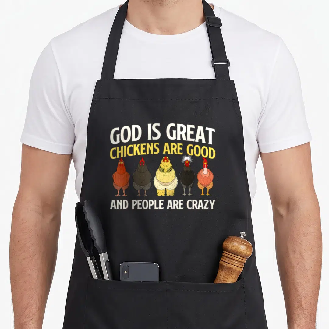 God chicken apron - Five cartoon chickens in brown black yellow and red with text God Is Great Chickens Are Good — shown on a black cotton canvas apron against a white background