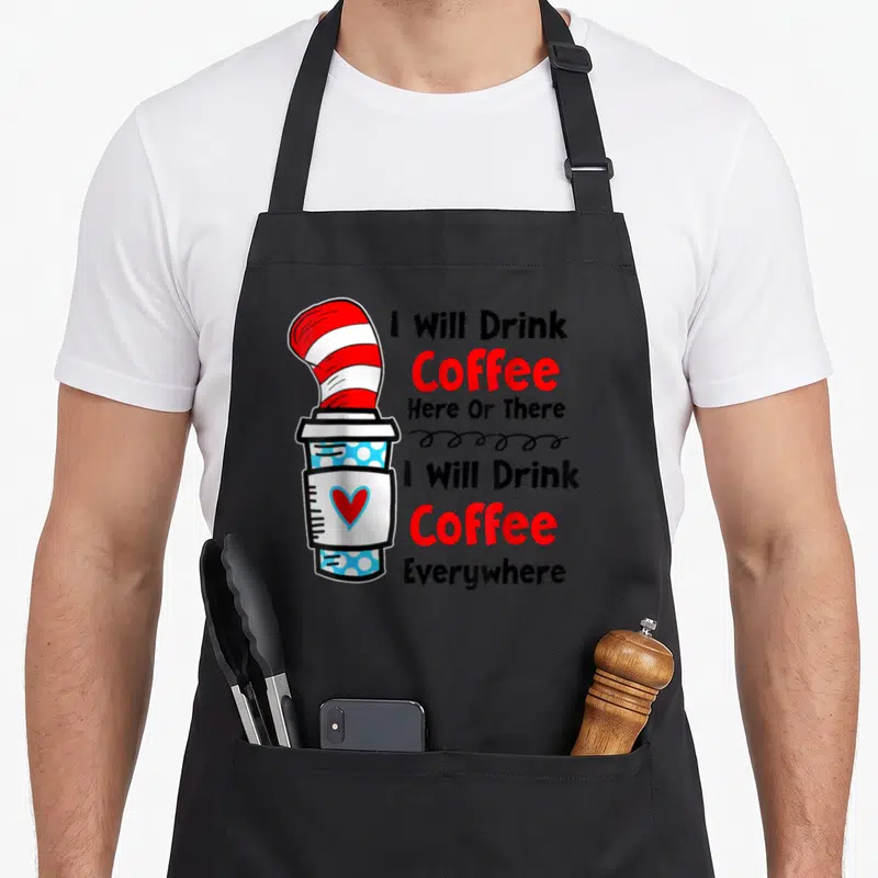 Teaching drink teacher apron - Cartoon coffee cup with red white striped hat and text I Will Drink Coffee Here Or There — shown on a black cotton canvas apron against a white background