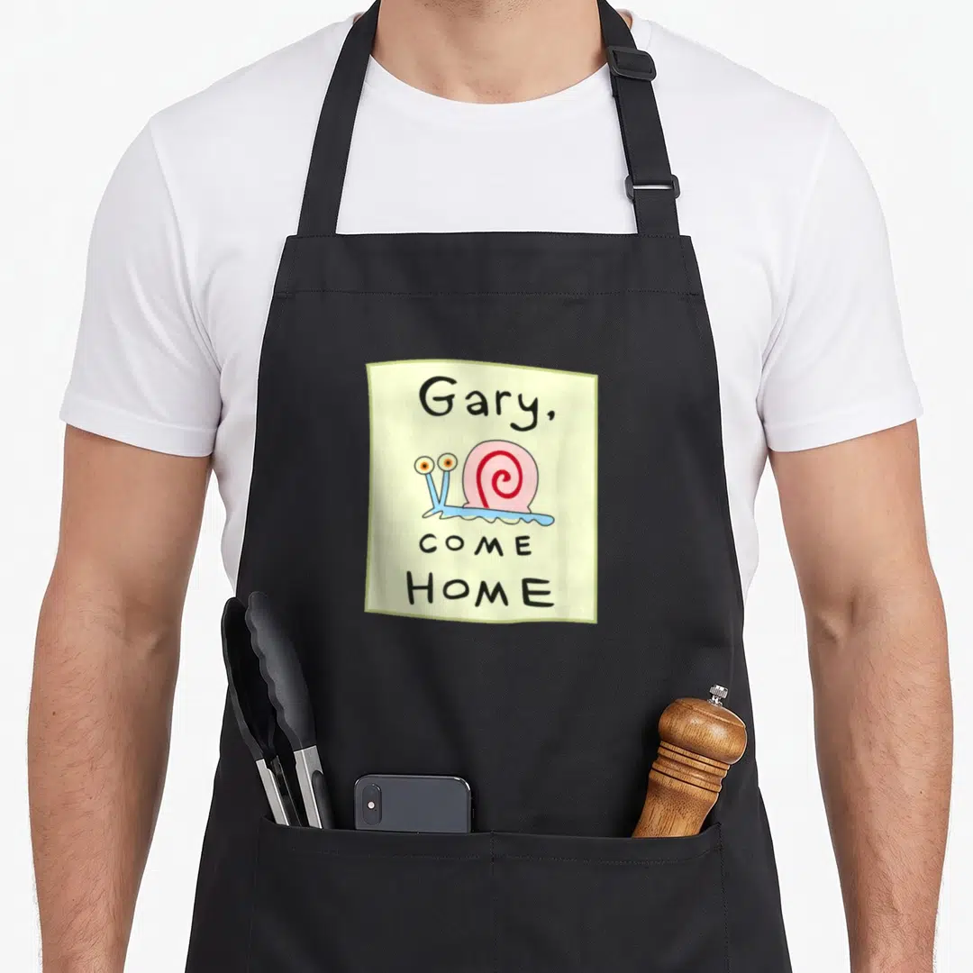 Come snail apron - Cartoon snail on pale yellow square with text Gary Come Home in black, blue, and pink — shown on a black cotton canvas apron against a white background