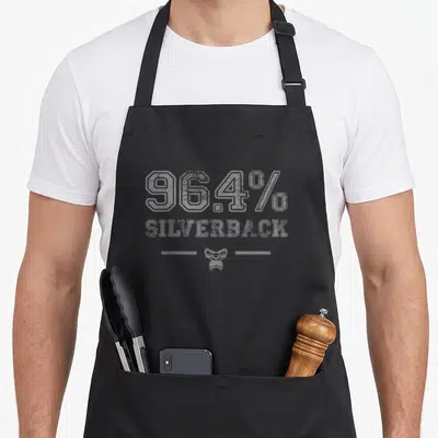 Silverback building apron - Grey distressed 96.4% SILVERBACK text and small gorilla head icon — shown on a black cotton canvas apron against a white background