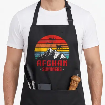 Afghan summer aprons - Retro sun stripes mountains planes AFGHAN SUMMERS text — shown on a black cotton canvas apron against a white background