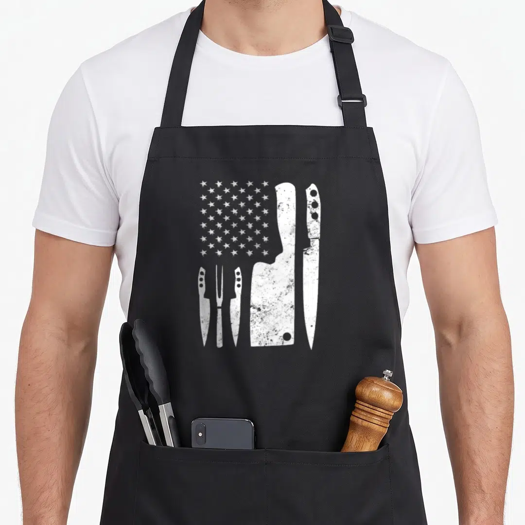 Knife 4th of july apron - Five white distressed knives and white stars arranged in a partial flag pattern on canvas — shown on a black cotton canvas apron against a white background