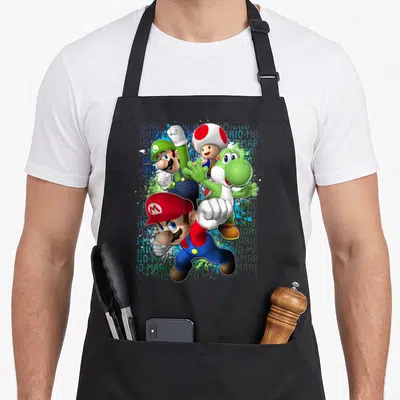 Action paint splatter apron - Mario, Luigi, Toad, Yoshi cartoon group with repeated MARIO text background in red blue — shown on a black cotton canvas apron against a white background