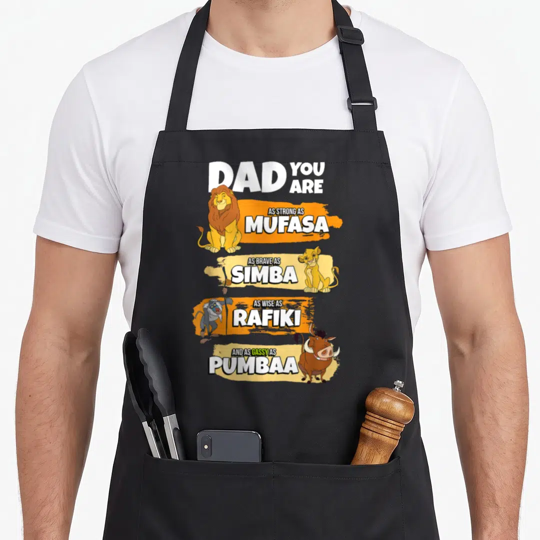 Stack lion dad apron - Vertical stack of Mufasa Simba Rafiki Pumbaa with white text on orange and yellow brushstrokes — shown on a black cotton canvas apron against a white background