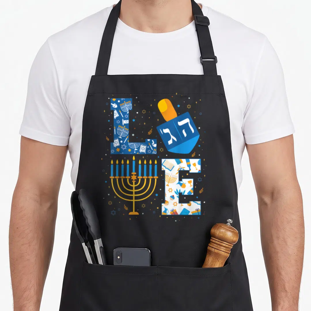 Hanukkah holiday christmas aprons - LOVE text formed by menorah, dreidel with Hebrew letters, and Hanukkah pattern — shown on a black cotton canvas apron against a white background