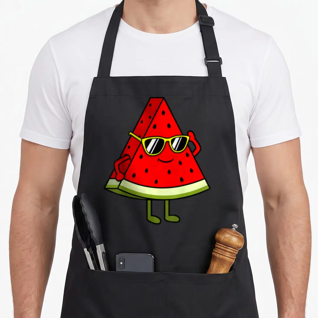 Funny summer watermelon apron - Cartoon watermelon slice wearing yellow sunglasses with red arms and green legs — shown on a black cotton canvas apron against a white background
