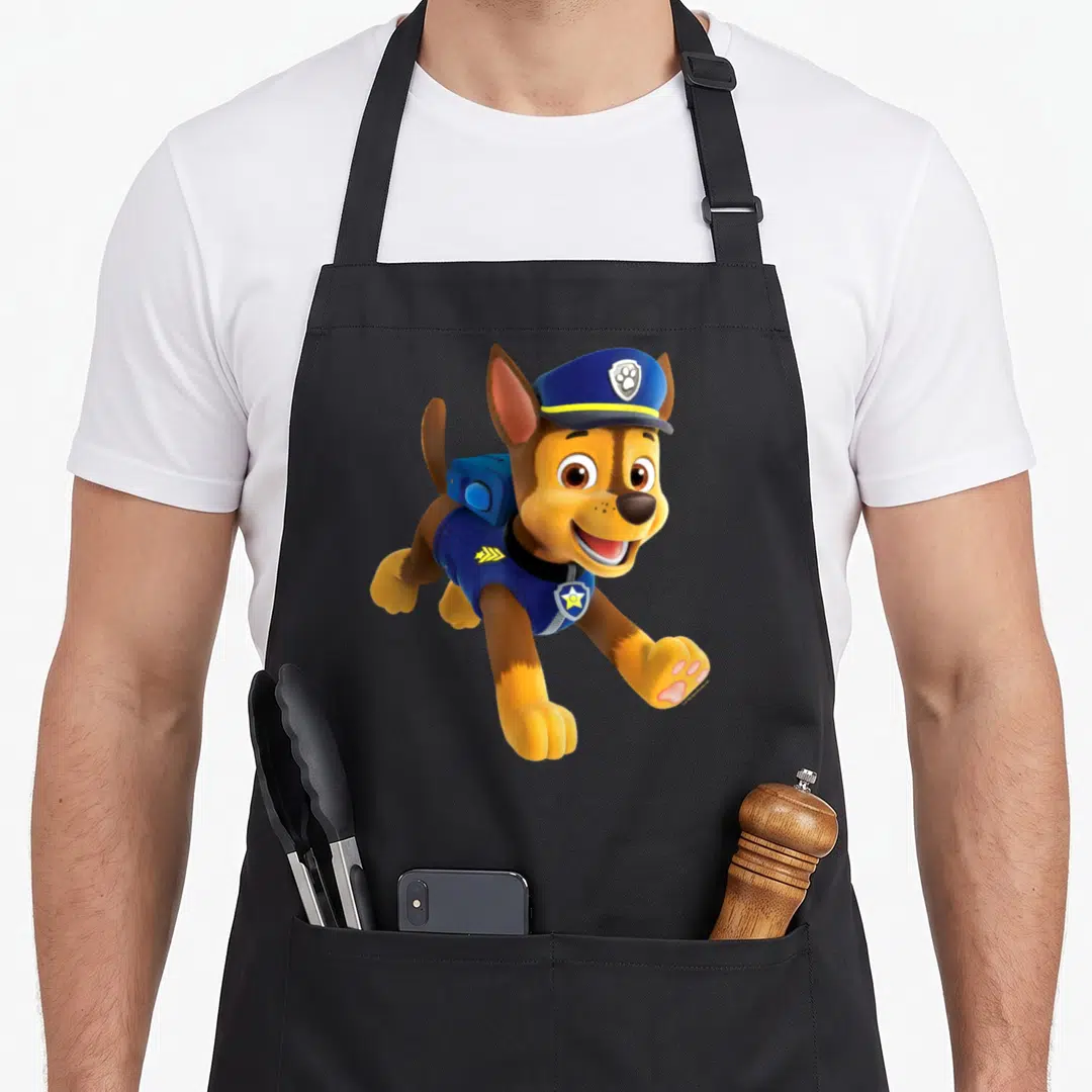 Funny chase birthday apron - Cartoon brown dog in blue hat and vest with yellow accents leaping forward — shown on a black cotton canvas apron against a white background