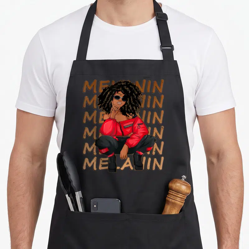 Melanin hair apron - Woman crouching in front of six stacked Melanin words in brown, red, and black — shown on a black cotton canvas apron against a white background