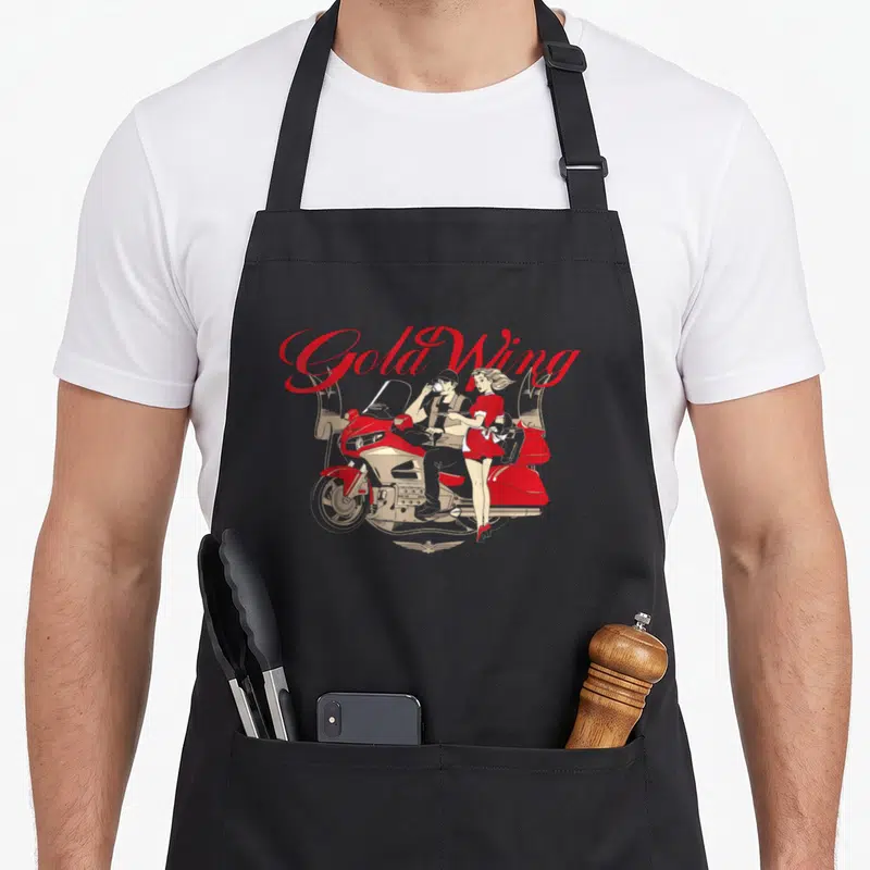 Goldwing motorcycle apron - Retro red script Gold Wing text above a couple on a red motorcycle with a wing logo — shown on a black cotton canvas apron against a white background