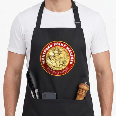 Montford military apron - Circular red and gold emblem with five soldiers and text MONTFORD POINT MARINES 1942 1949 — shown on a black cotton canvas apron against a white background