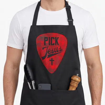 Pick jesus christian apron - Red guitar pick shape with distressed grey PICK Jesus text and cross — shown on a black cotton canvas apron against a white background