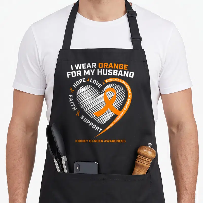 Family husband wife aprons - Orange ribbon inside white sketched heart with supportive text for kidney cancer awareness — shown on a black cotton canvas apron against a white background