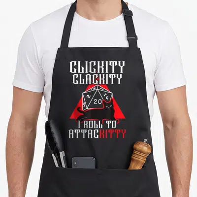 Role video game apron - Black cat lying in front of white d20 die and red triangle with Clickity Clackity text — shown on a black cotton canvas apron against a white background