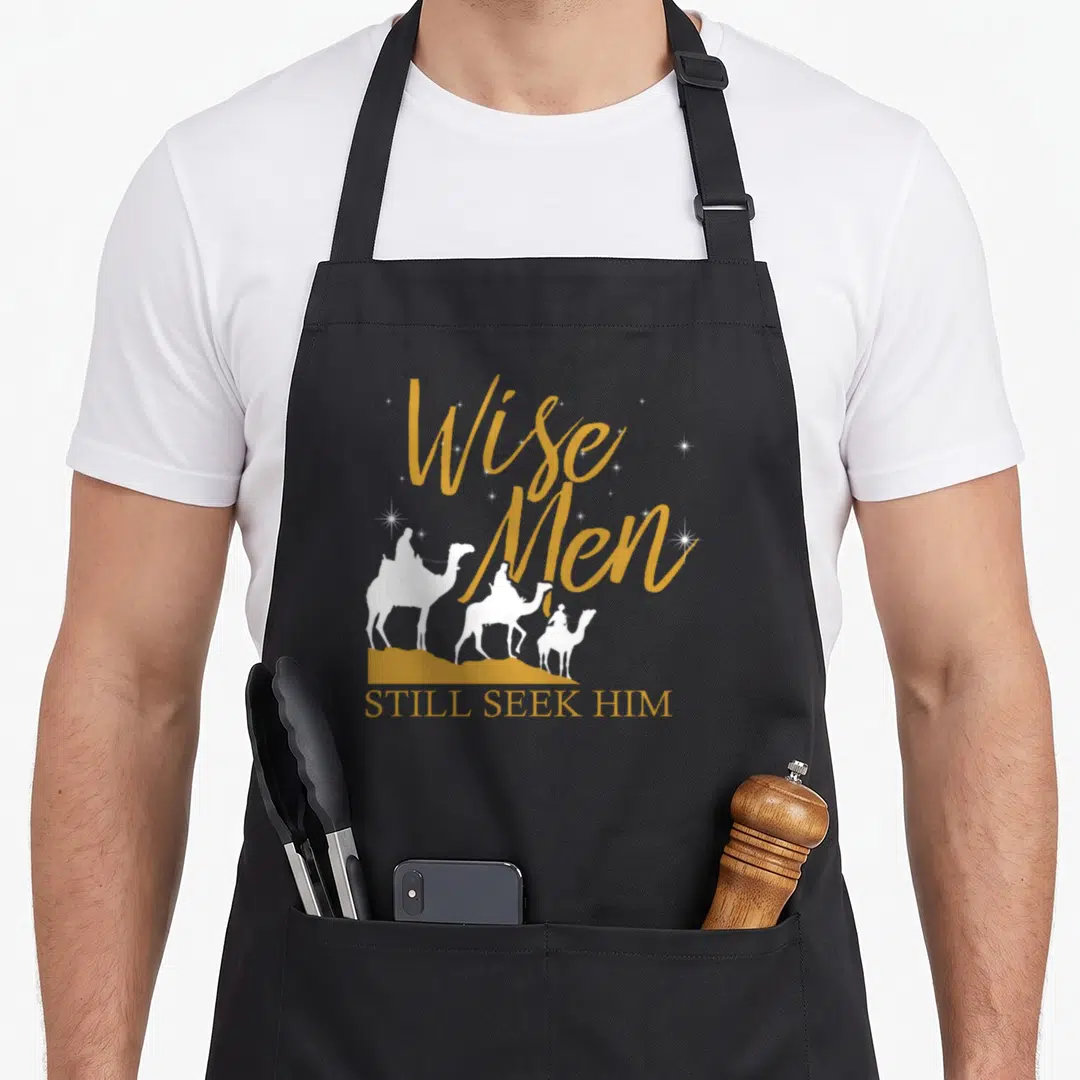 Wise prayer apron - Three white camel riders on gold hill under gold script text and stars — shown on a black cotton canvas apron against a white background