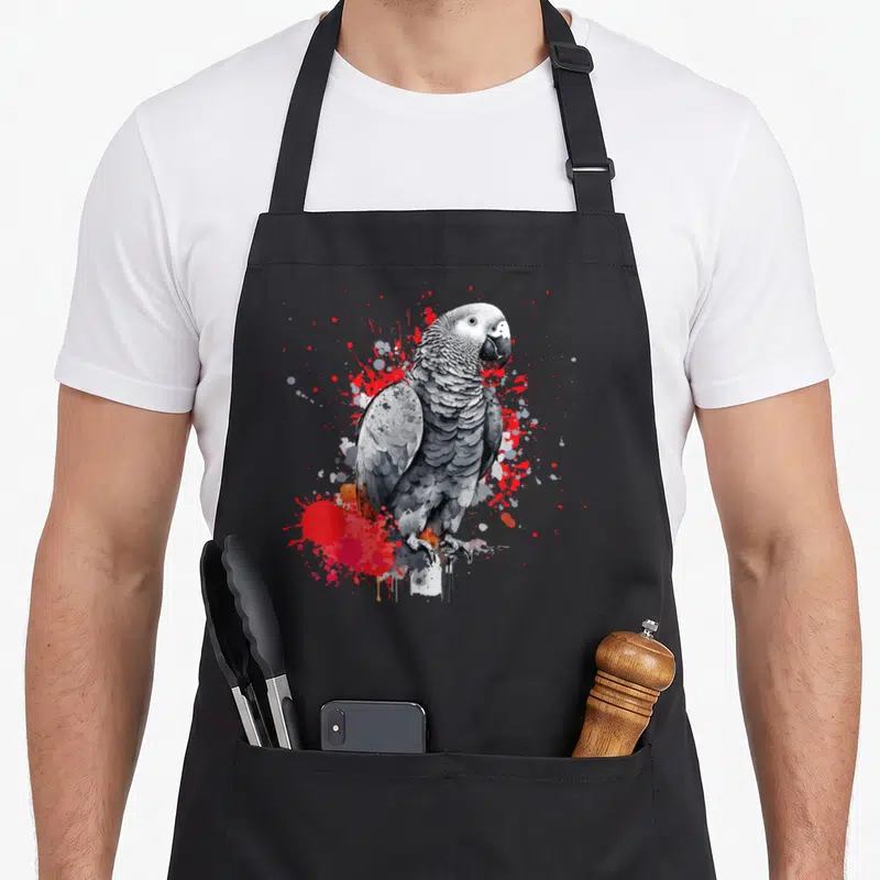 Parrot african aprons for men - Realistic grey parrot with red and white paint splatters on black apron — shown on a black cotton canvas apron against a white background