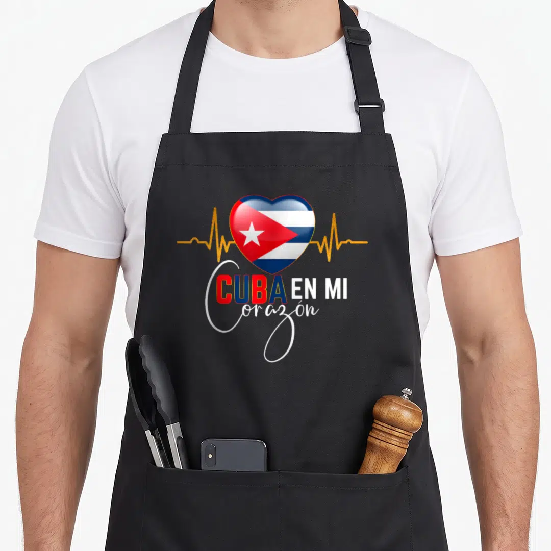 Corazon pride apron - Heart with Cuban flag and gold heartbeat line above CUBA EN MI corazón text — shown on a black cotton canvas apron against a white background