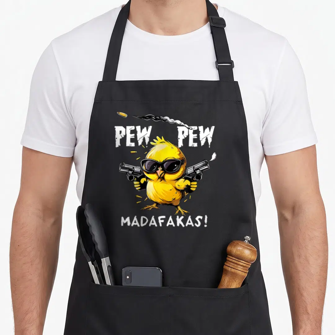 Pew mens joke aprons - Yellow cartoon chick holding revolvers with PEW PEW MADAFAKAS text on grey background — shown on a black cotton canvas apron against a white background