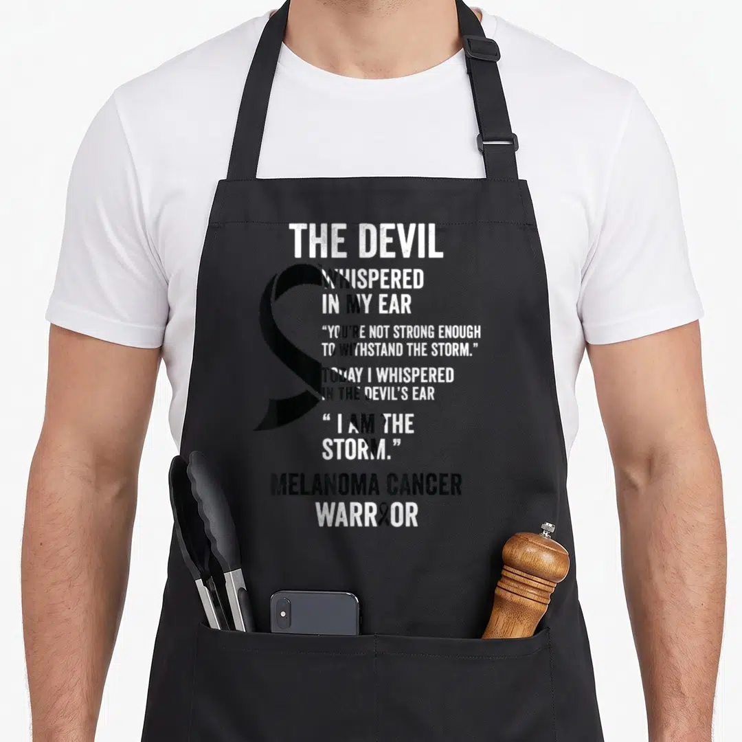 Melanoma devil's apron - Black awareness ribbon and white text reading The Devil Whispered In My Ear Melanoma Cancer — shown on a black cotton canvas apron against a white background
