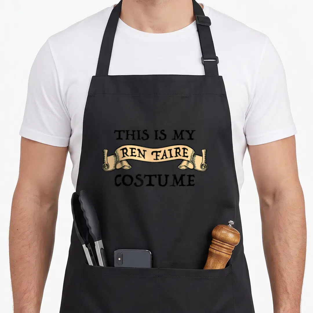 Fest renaissance apron - Stacked text THIS IS MY REN FAIRE COSTUME with tan banner and black lettering — shown on a black cotton canvas apron against a white background
