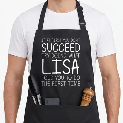 Lisa christmas apron - White stacked text reading If At First You Don't Succeed Try Doing What Lisa Told You To Do — shown on a black cotton canvas apron against a white background