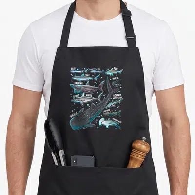 Specy face apron - Realistic shark species chart with white labels and blue bubbles on grey background — shown on a black cotton canvas apron against a white background