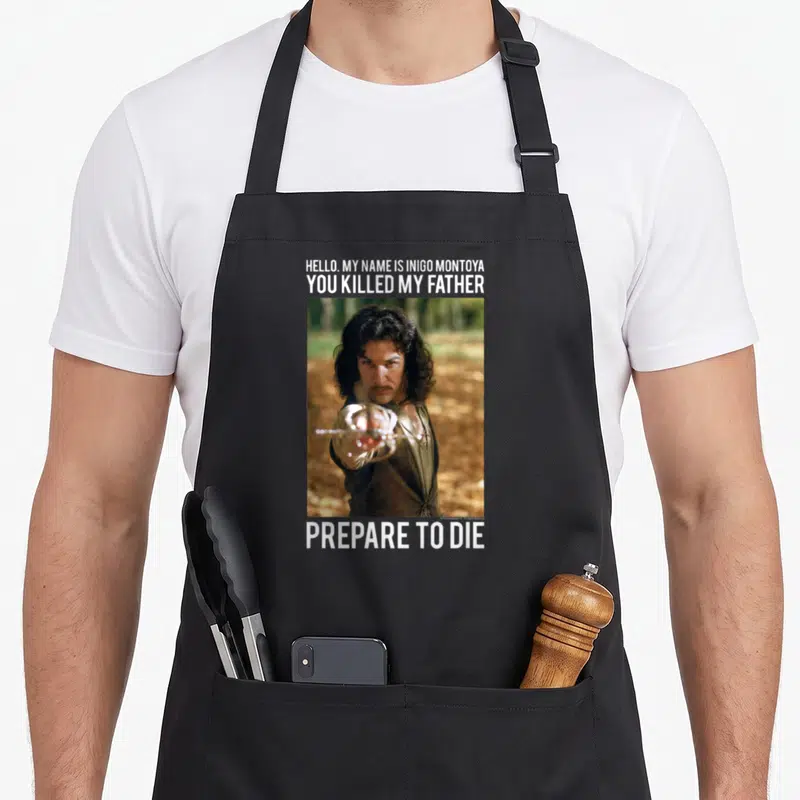 Hello princess apron - Photo of man pointing sword with Hello My Name Is Inigo Montoya You Killed My Father Prepare — shown on a black cotton canvas apron against a white background