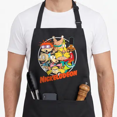 Nick 90s character aprons - Cartoon characters clustered in white circle with NICKELODEON in orange letters below — shown on a black cotton canvas apron against a white background