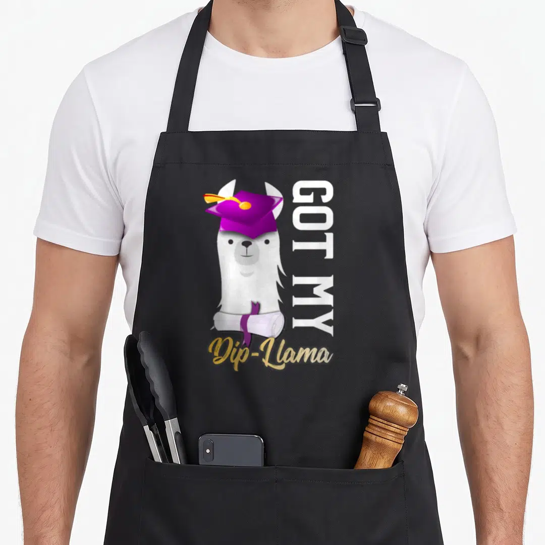 Dip graduation apron - Cartoon white llama in purple cap holding diploma with GOT MY Dip-Llama text — shown on a black cotton canvas apron against a white background