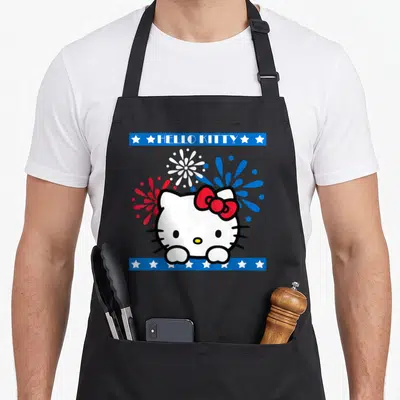 Americana 4th of july apron - Hello Kitty cartoon face with red bow amidst red white and blue fireworks framed by blue — shown on a black cotton canvas apron against a white background