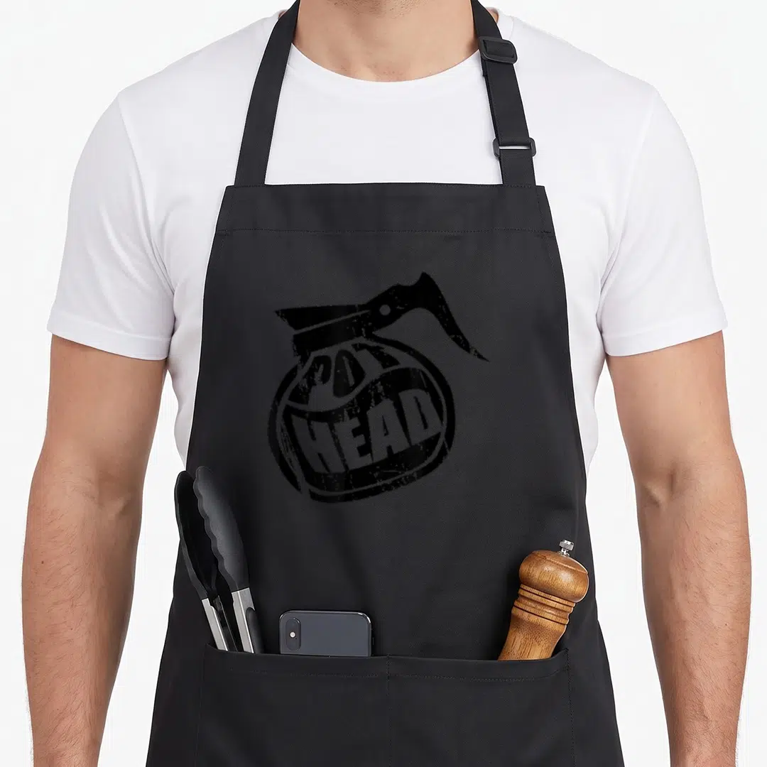 Pot coffee apron - Black teapot silhouette with distressed white POT HEAD text printed on the body — shown on a black cotton canvas apron against a white background