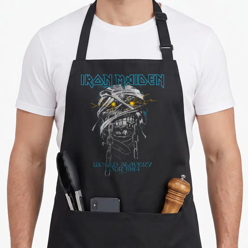 Funny powerslave mummy and me aprons - Distressed skeleton with lightning eyes and Iron Maiden World Slavery Tour 1984 — shown on a black cotton canvas apron against a white background