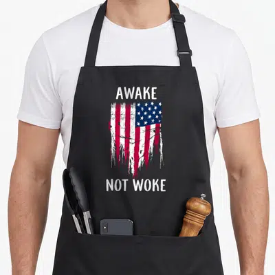 Speech free apron - Distressed USA flag between AWAKE above and NOT WOKE below text — shown on a black cotton canvas apron against a white background