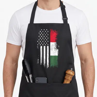 Hungarian american flag apron - Composite flag design with distressed white stars stripes and red white green — shown on a black cotton canvas apron against a white background