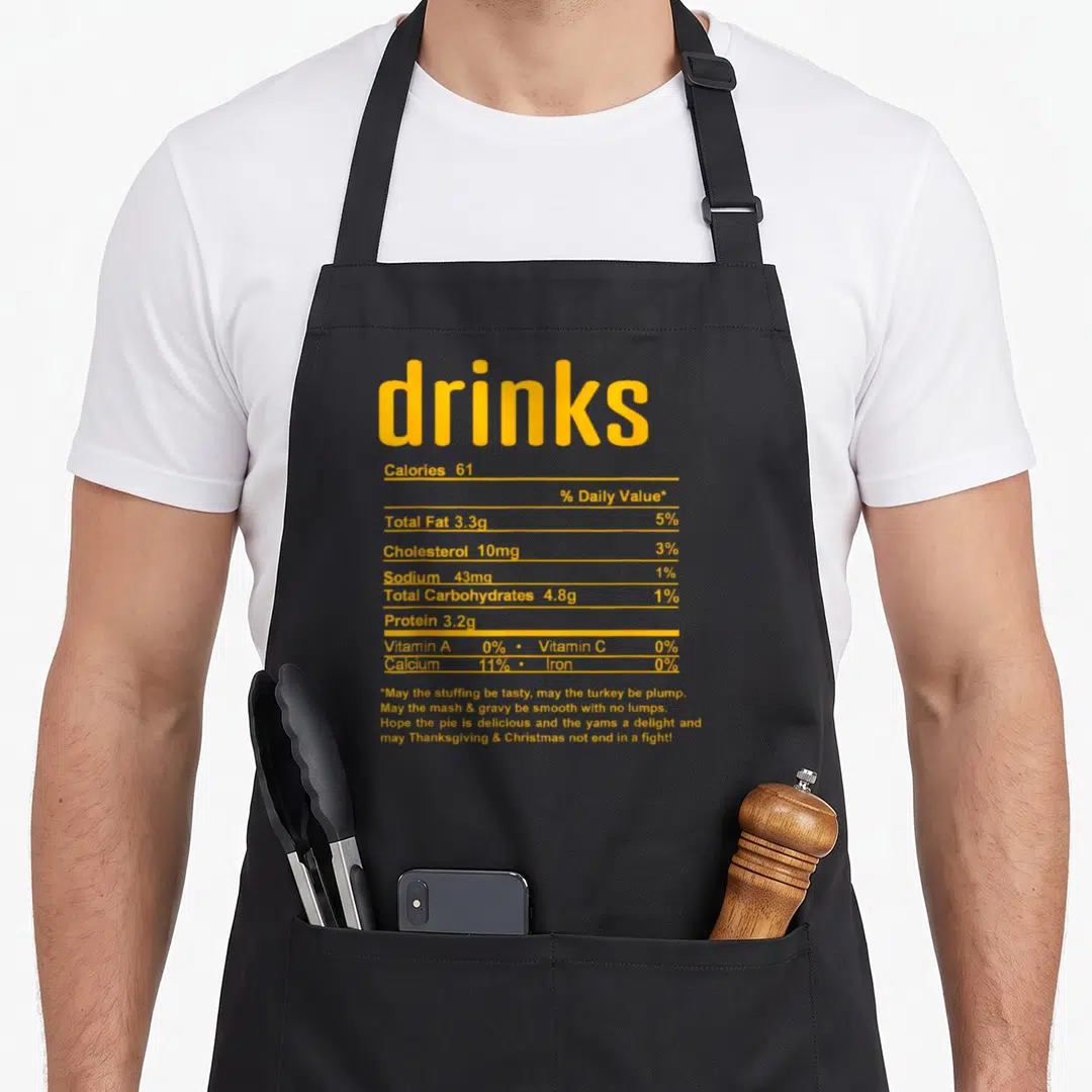Fact thanksgiving aprons - Yellow nutrition label text for drinks listing calories and holiday wishes — shown on a black cotton canvas apron against a white background