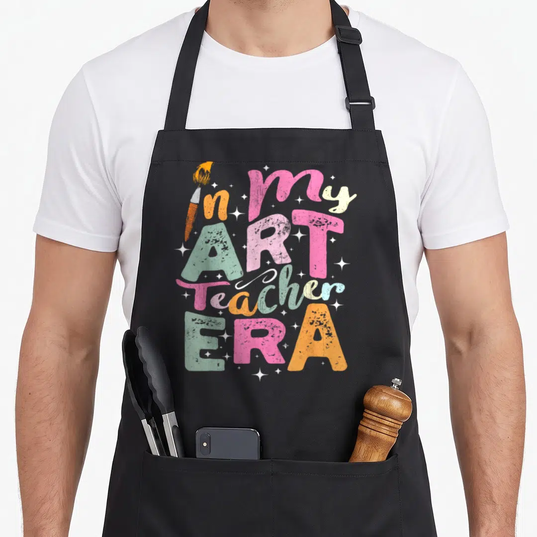Era teaching teacher apron - Stacked colorful text in my ART Teacher ERA with paintbrush and white stars — shown on a black cotton canvas apron against a white background