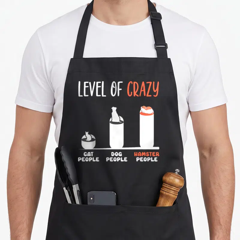 Hamster cat apron - Bar chart with white bars topped by cat, dog, and hamster silhouettes labeled level of crazy — shown on a black cotton canvas apron against a white background