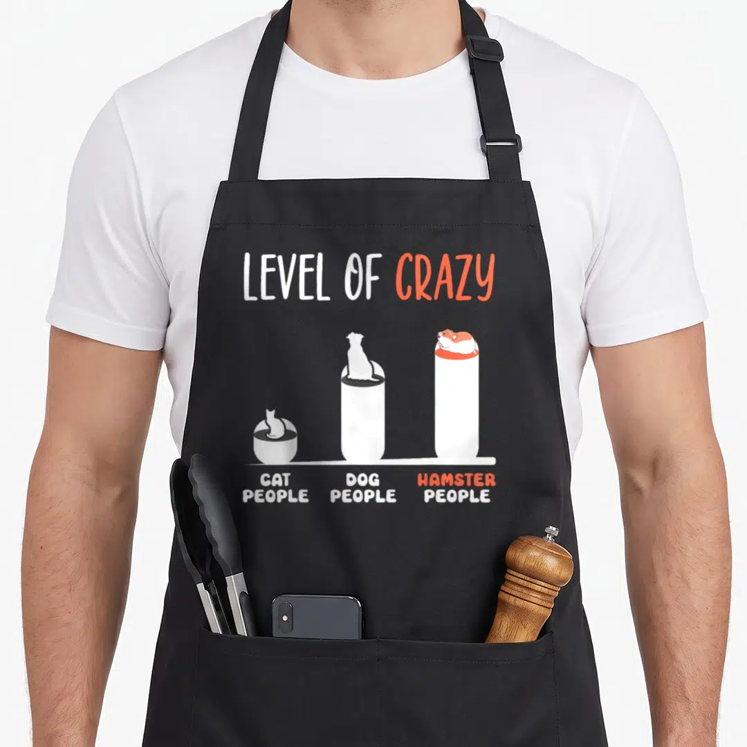Hamster cat apron - Bar chart with white bars topped by cat, dog, and hamster silhouettes labeled level of crazy — shown on a black cotton canvas apron against a white background