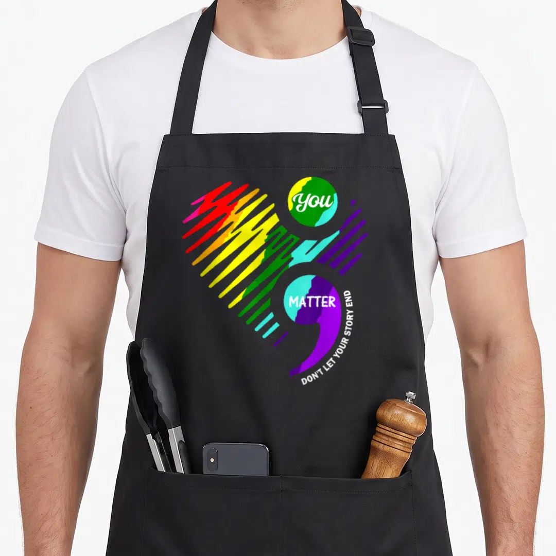 Semicolon mental health awareness apron - Rainbow semicolon with You matter text inside dots and curved slogan along — shown on a black cotton canvas apron against a white background