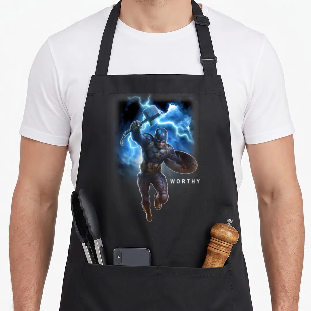 Endgame worlds greatest apron - Captain America holding Mjolnir and shield with WORTHY text and lightning — shown on a black cotton canvas apron against a white background