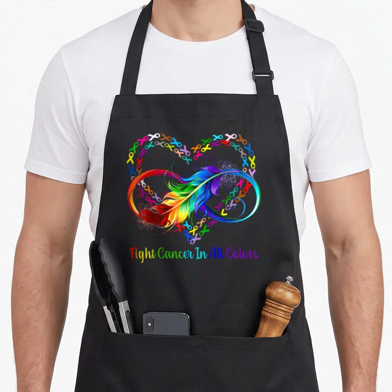 Fight rainbow apron - Rainbow feather infinity symbol surrounded by multicolored ribbon heart with supportive text below — shown on a black cotton canvas apron against a white background