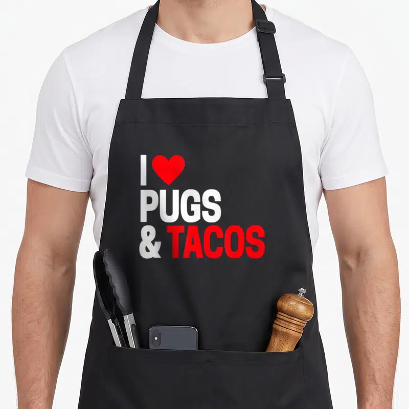 Taco custom dog apron - Red heart and text reading I Pugs & Tacos in white and red typography — shown on a black cotton canvas apron against a white background