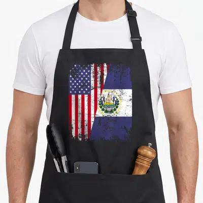 Root salvadoran apron - Merged US and El Salvador flags with distressed texture and printed text — shown on a black cotton canvas apron against a white background