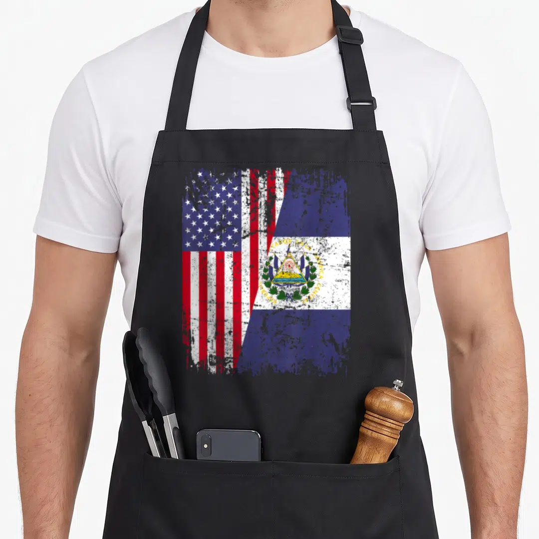 Root salvadoran apron - Merged US and El Salvador flags with distressed texture and printed text — shown on a black cotton canvas apron against a white background