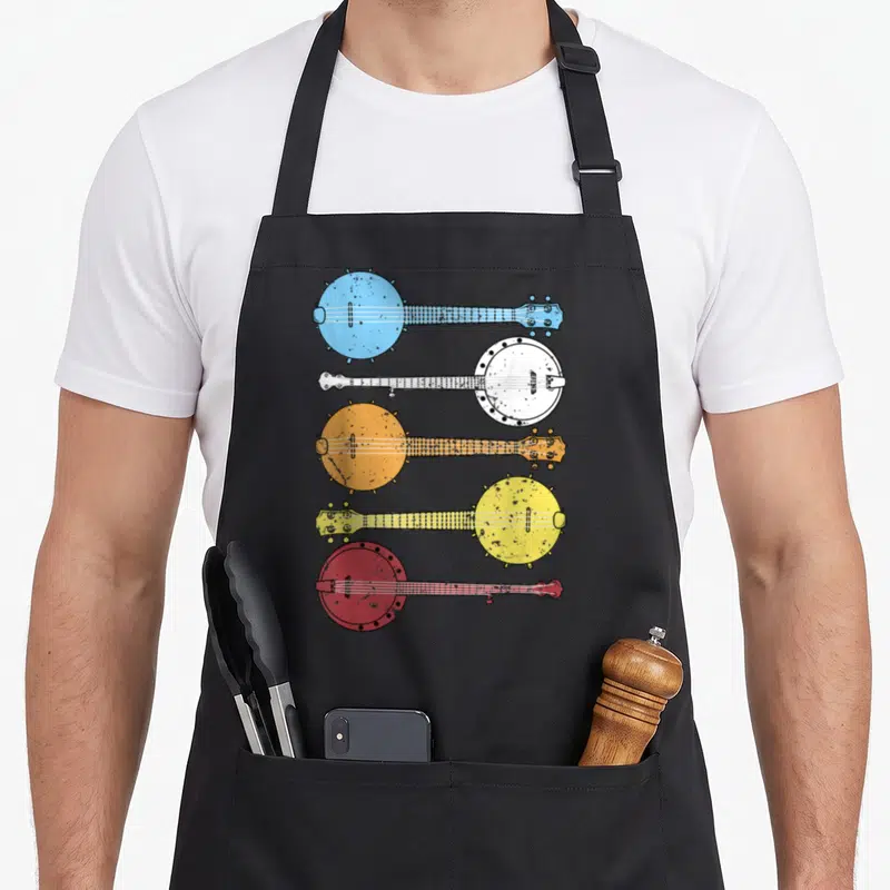 Banjo country apron - Five banjos in blue white orange yellow red stacked vertically facing alternating directions — shown on a black cotton canvas apron against a white background