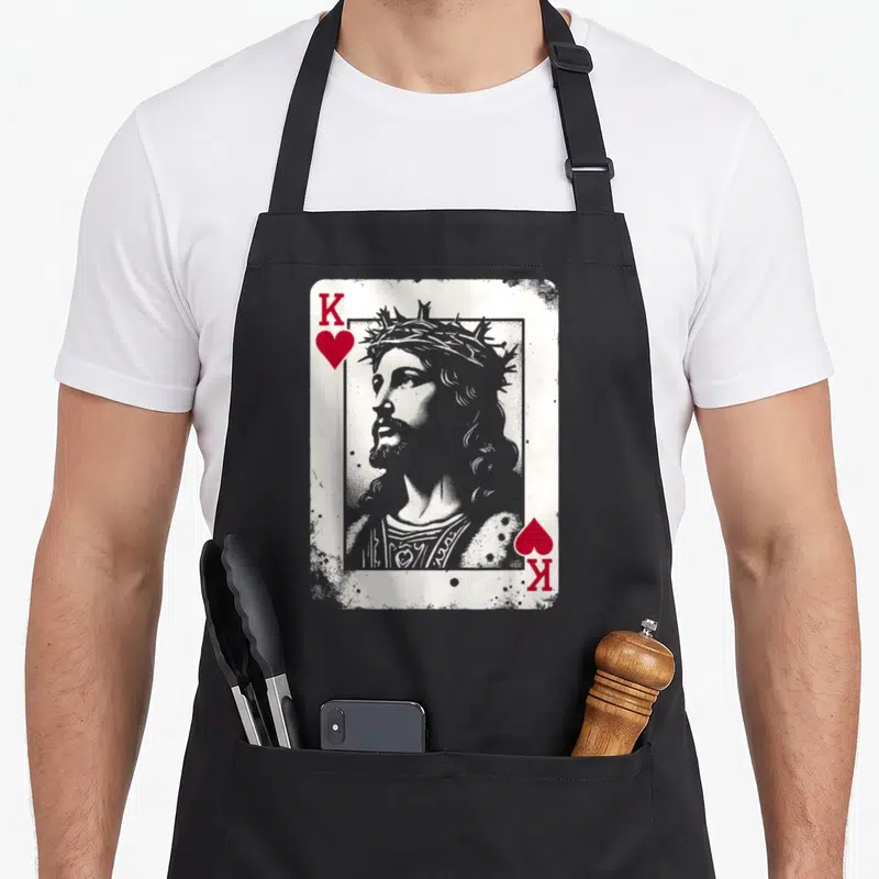 Jesus king apron - Distressed playing card portrait of Jesus with red K and heart symbols in grey and white — shown on a black cotton canvas apron against a white background