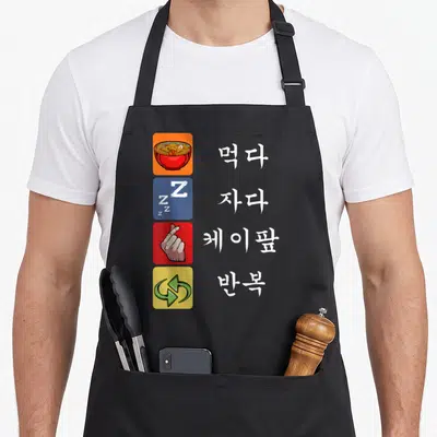 Sleep korean apron - Four rows of Korean text next to noodle, Zs, finger heart, and recycle icons in orange blue red — shown on a black cotton canvas apron against a white background