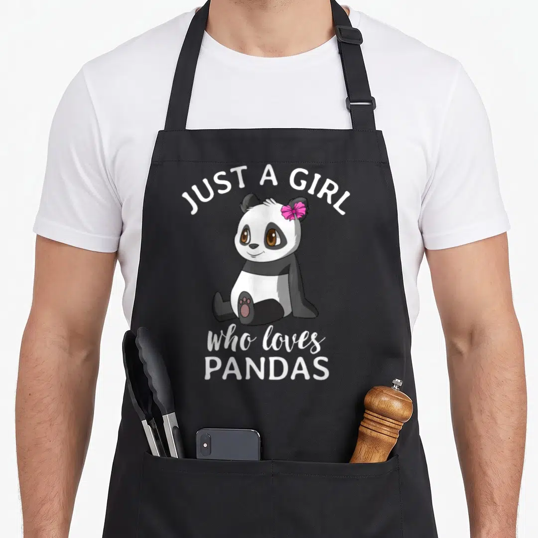 Pandas kawaii apron - Cartoon panda with pink bow and text JUST A GIRL who loves PANDAS — shown on a black cotton canvas apron against a white background